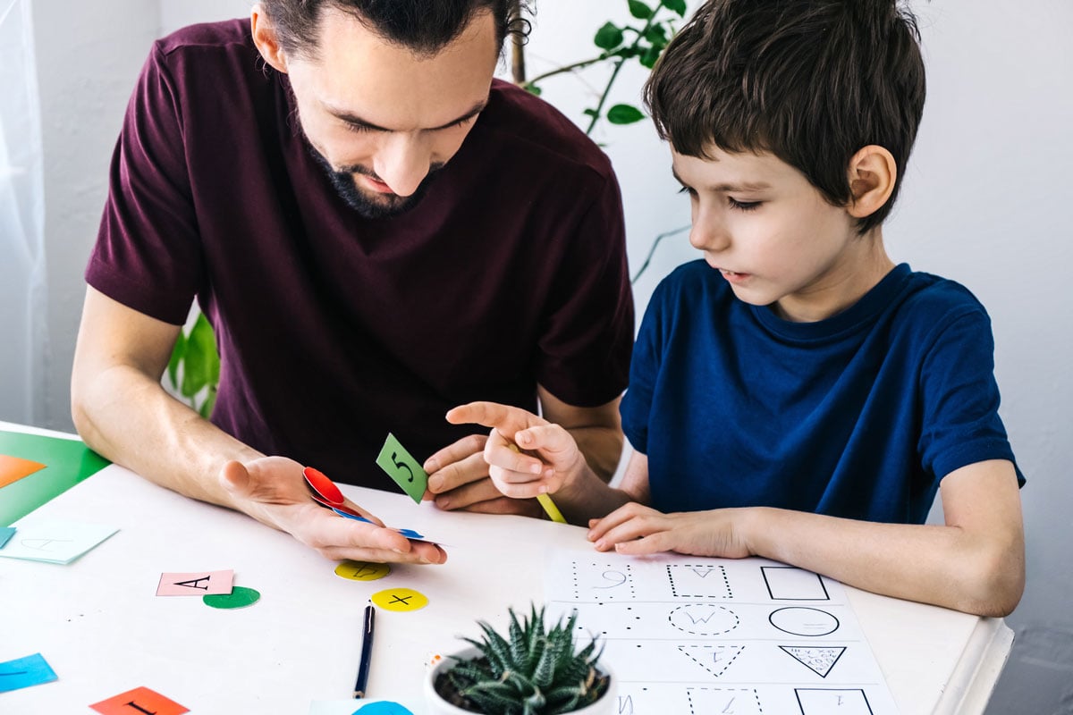 Autism schoolboy during therapy at home with his tutor
