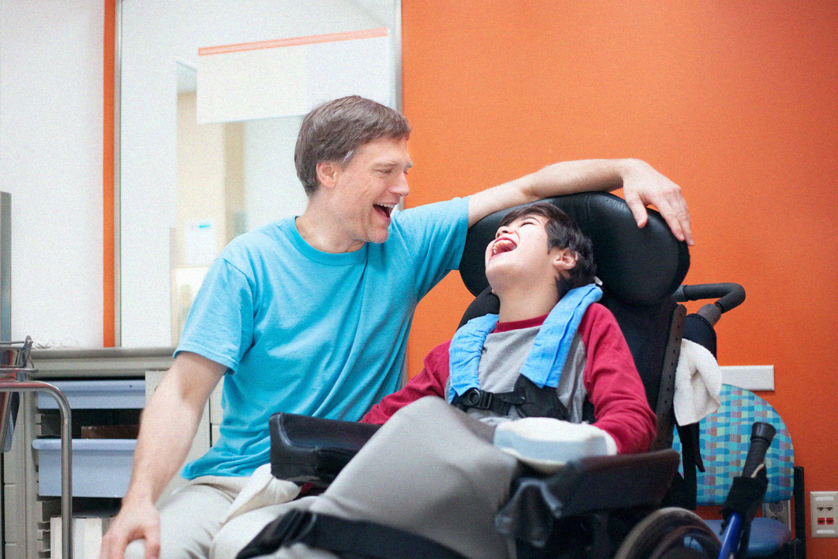Disabled boy in wheelchair talking with father
