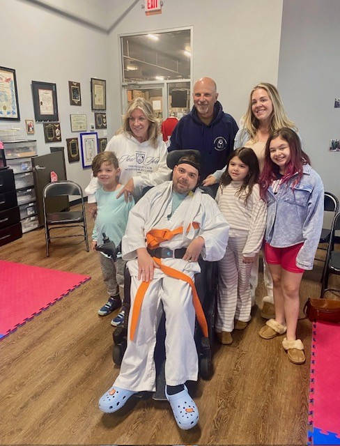 Nick with orange mixed martial art belt surrounded by his family  members