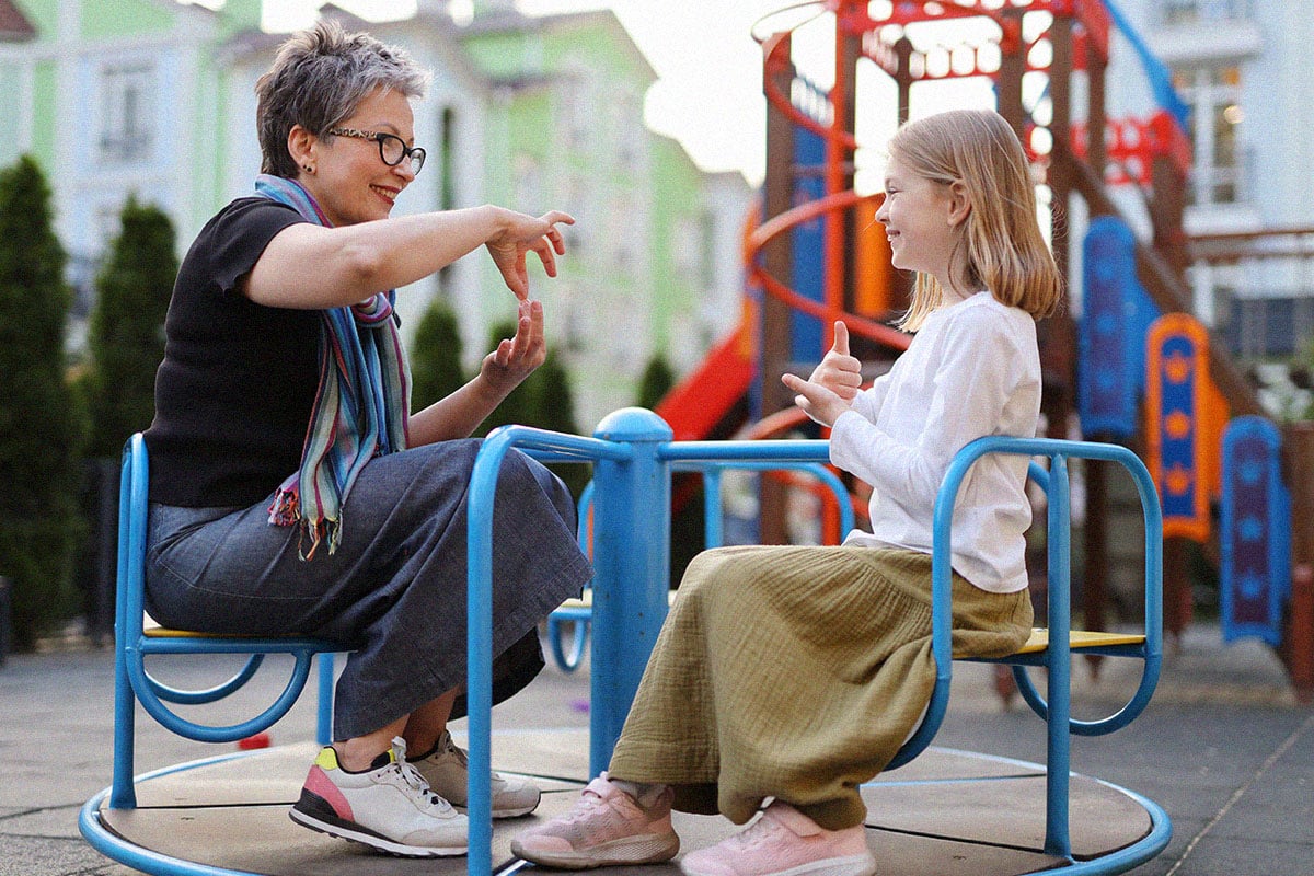 a woman communicates with a girl in sign language at the park