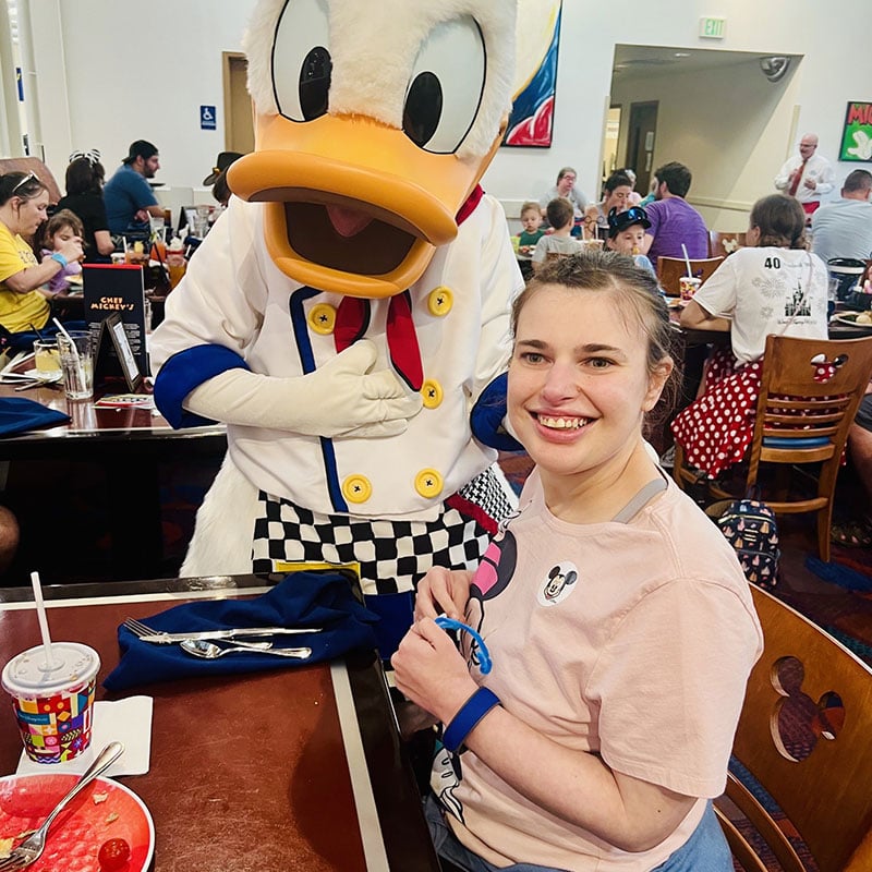woman in disney dining hall smiling with donald duck