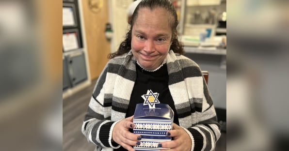 woman smiling while holding a blue box decorated with a Star of David