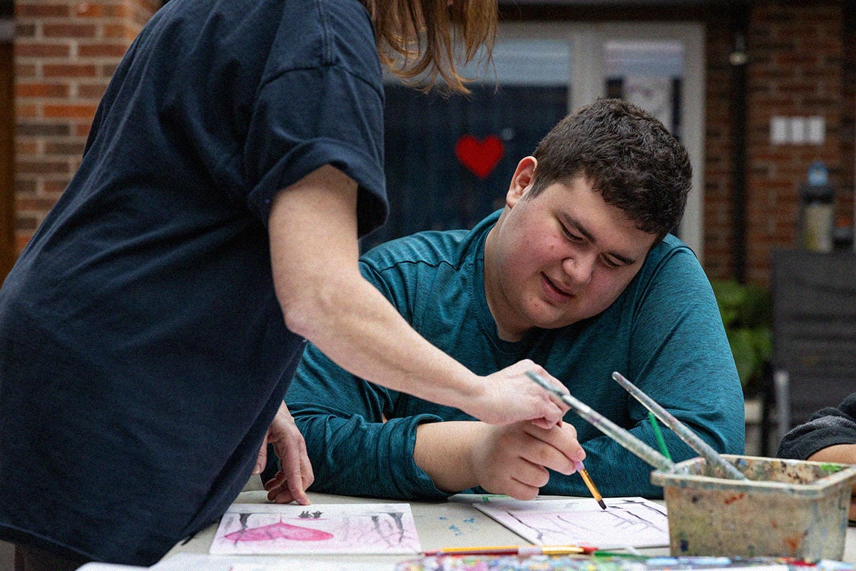 boy painting with teacher outside home