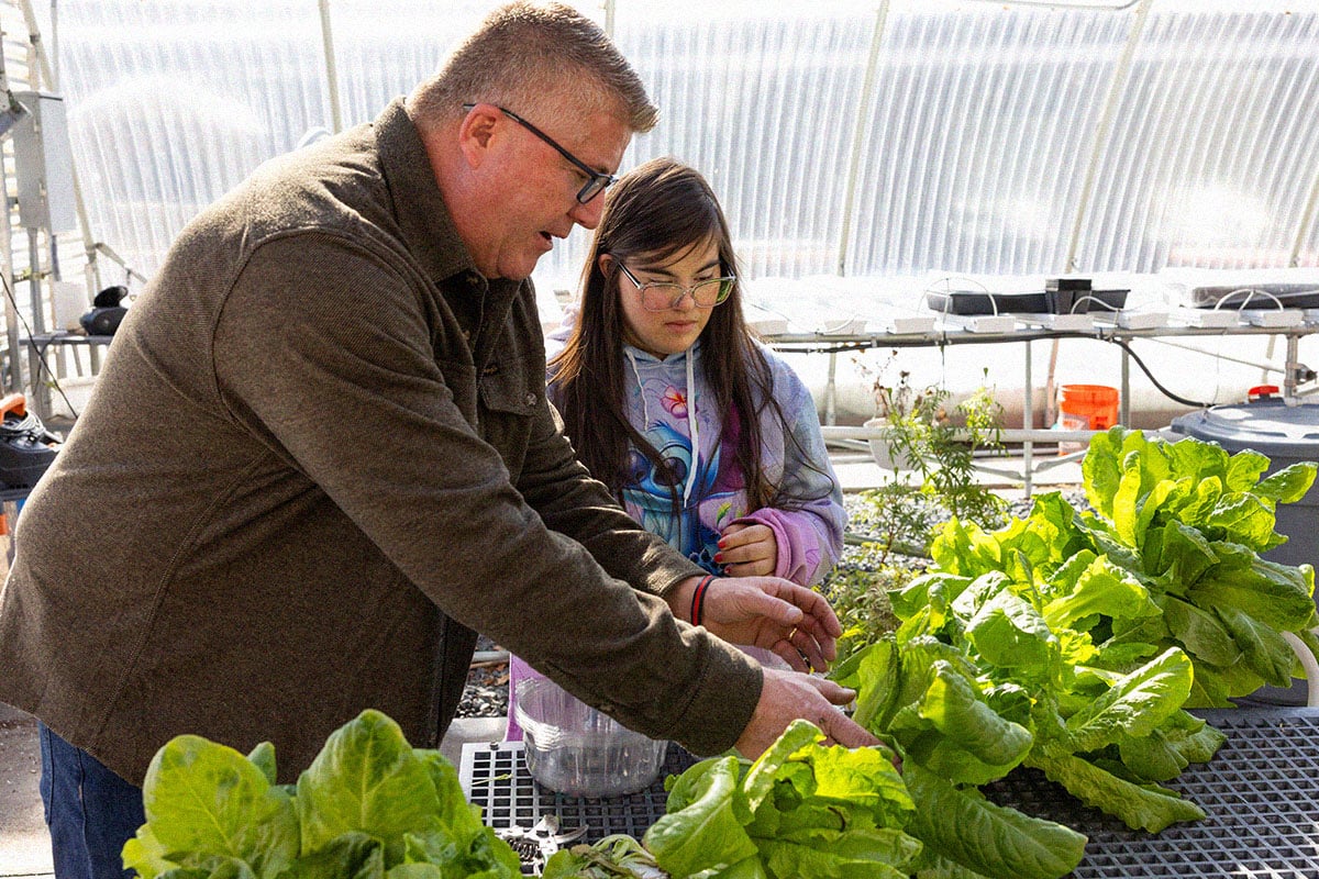 instructor working with student in greenhouse