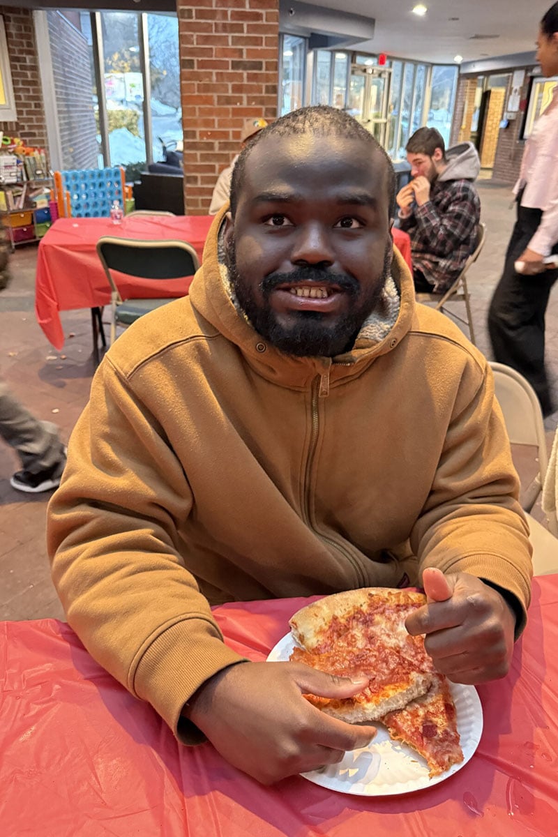 male-student-smiling-while-eating-pizza