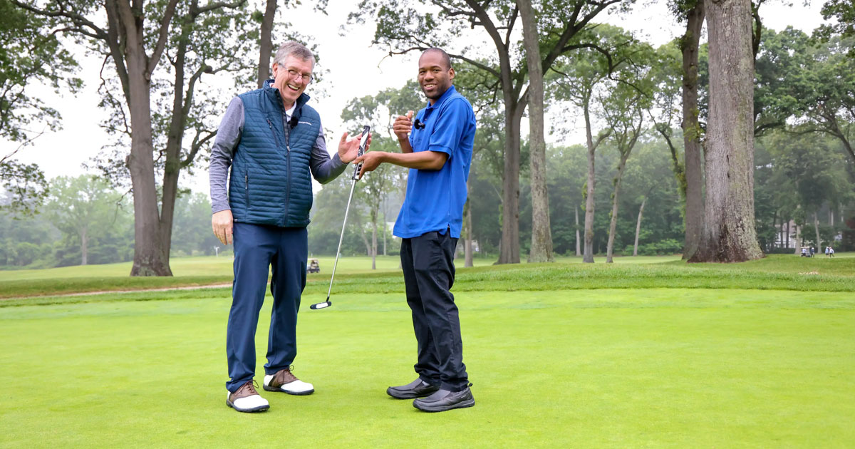 two men standing on the greens holding a putter